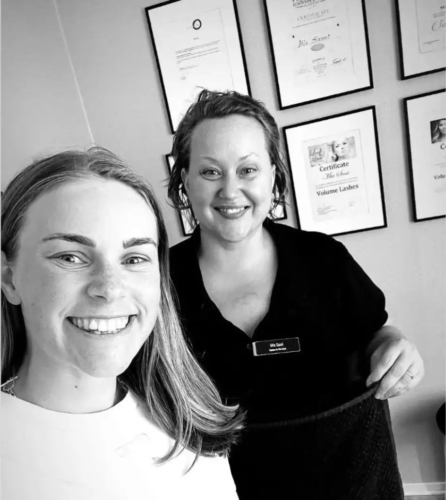 En glad kund tillsammans med Mia framför diplomen i behandlingsrummet hos Optima by Mia Sassi.
